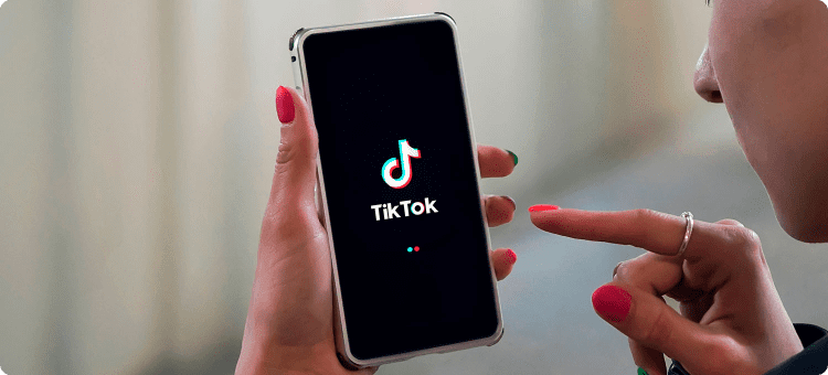 Manos de una persona sosteniendo su celular con la pantalla de inicio de TikTok